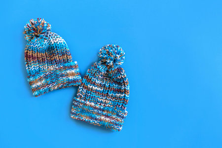Autumn is coming soon. Stylish fashionable blue knitted hats on a blue background. Minimal fashion....