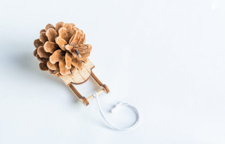 A toy sleigh brought a pine cone. Eco-friendly simple gift on a white background concept. Top view.