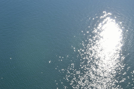 Glare of sun on the water surface. Blue water, ripples, sun reflection in the water.