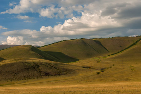 Scenic view of the mountains, hills covered with vegetation, forest, blue sky and clouds in sunlightの写真素材