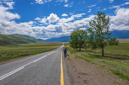 A man photographs the beautiful prairie landscape with road and single trees.の写真素材