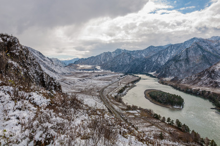 Beautiful landscape with mountains, a river, island and road covered with the first snow autumn.の写真素材