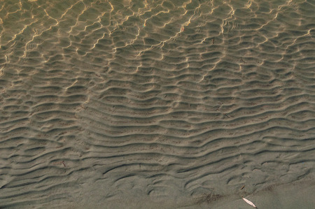 Waves on the sand from the water flowの写真素材