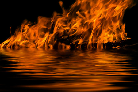 The flames from the fire on a black background with reflection in waterの写真素材