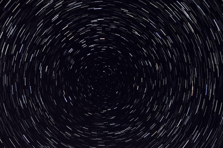 Abstract decorative background with swirls traces of stars revolving around the North Star on the background of the black night sky, shot long exposureの写真素材