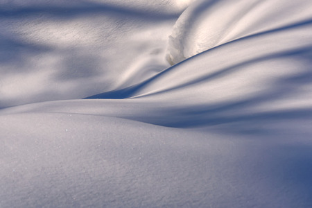Winter background with beautiful curves and shadows on the snow drifts on a sunny dayの写真素材
