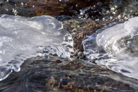 Abstract spring natural background with patterns of ice and snow on the background of the rapid flow...