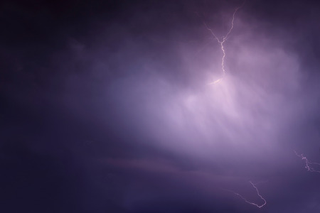 Beautiful natural background with a flash of lightning in dark blue clouds during thunderstormsの写真素材