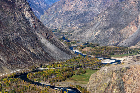 The picturesque autumnal top view on the mountains, cliffs and beautiful winding river in a valley between the mountainsの写真素材