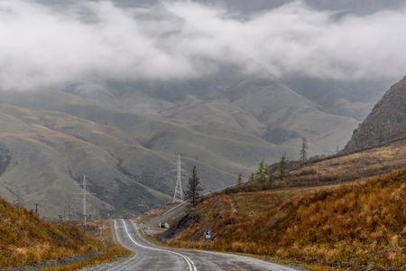Scenic view from the wet asphalt road in the mountains in autumn cloudy weather with beautiful fog and rainの写真素材