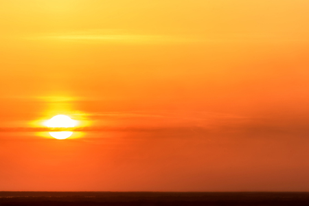 Colorful abstract background with sun and clouds against the background of a fiery orange sky at sunsetの写真素材