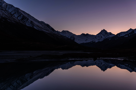 Amazing colorful sunset with a glacier and snowy mountains reflected in the smooth water of the lake in autumnの写真素材