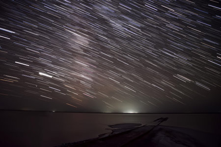 Beautiful view of the night sky with stars in the form of tracks over a salt lake and rails into the...