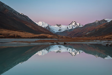 Amazing autumn landscape with a lake, a glacier, snowy mountains and their reflections in the water at dawn. Altai, Russiaの写真素材