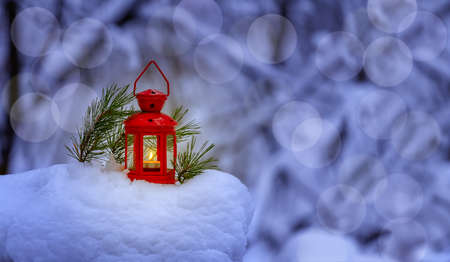 Festive winter background. Merry Christmas and Happy New Year greeting card. Red lantern standing in a winter landscape.の写真素材