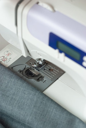 Household sewing machine stands on a table with a suit cloth