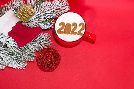 A cup of coffee with the numbers of the New Year, on a red background.