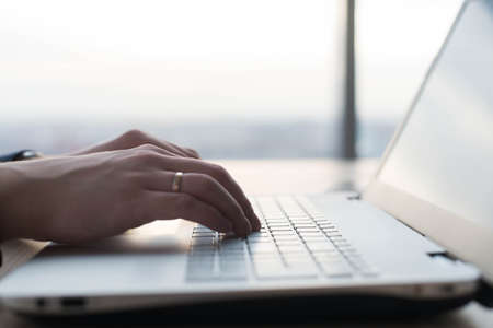 Hands typing on a laptop keyboard. A man works in an office at his workplace.の写真素材
