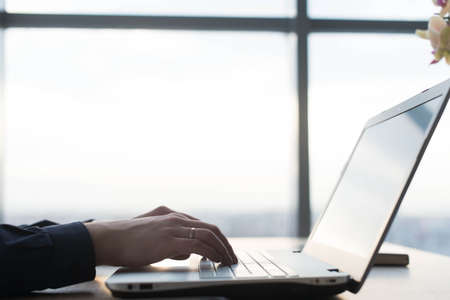 Hands typing on a laptop keyboard. A man works in an office at his workplace.の写真素材