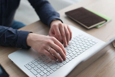 Hands typing on a laptop keyboard. A man works in an office at his workplace.の写真素材