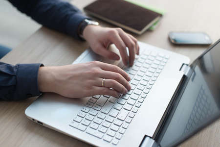 Hands typing on a laptop keyboard. A man works in an office at his workplace.の写真素材