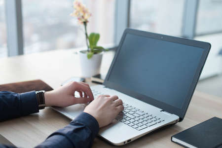 Hands typing on a laptop keyboard. A man works in an office at his workplace.の写真素材
