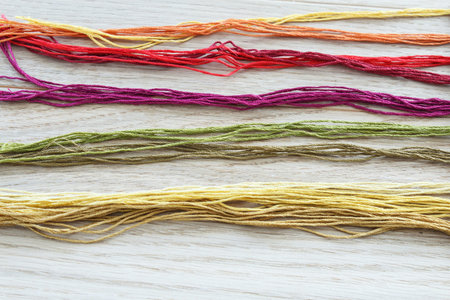 Threads for embroidery on a light wooden background. Background and texture.