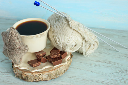 Yarn and knitting needles on a light blue background. Black coffee and chocolate.の写真素材