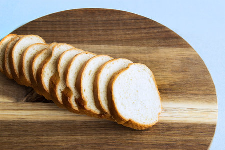 Slices of baguette on a wooden table. Fresh baguette on a wooden tray. Copy space. Top view.