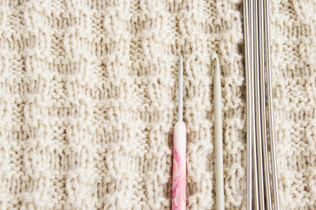 Knitting needles and hook on knitted background. Tools for female needlework. The concept of female...