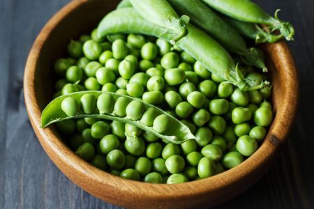 Green peas in a wooden bowl. Selective focus. Country style. The concept of healthy eating.の写真素材