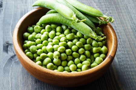 Green peas in a wooden bowl. Selective focus. Country style. The concept of healthy eating.の写真素材
