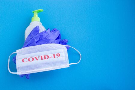 Medical mask, medical gloves and disinfectant on a blue background. Personal virus protection concept. Copy space.の写真素材