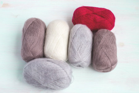 Threads for knitting natural tones on a light wooden background. Female hand-made hobby. Handicraft.