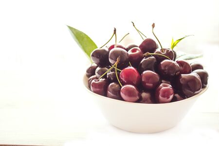 Sweet cherry in a bowl isolated on a white background. The concept of consuming natural products and supporting local producers. Close-up. Copy space.の写真素材