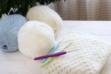 Cozy homely atmosphere. Balls for knitting in natural colors. Female hobby knitting. Blue, beige, white. Balls and hooks for the implementation of a knitted project. Materials for a creative project. Copy space.の写真素材