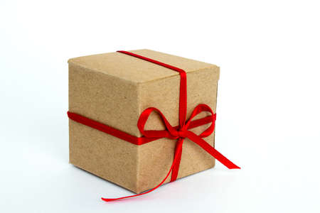 Gift box with red ribbon isolated on white. The concept of gifts for the holidays. Christmas and New Year. Cardboard box decorated with a red ribbon.の写真素材