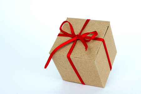 Gift box with red ribbon isolated on white. The concept of gifts for the holidays. Christmas and New Year. Cardboard box decorated with a red ribbon.の写真素材