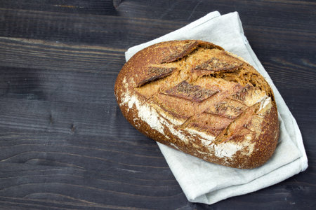 Rye bread on a dark wooden background. Fresh bread. Close-up. A loaf of bread. Top view. Copy space...