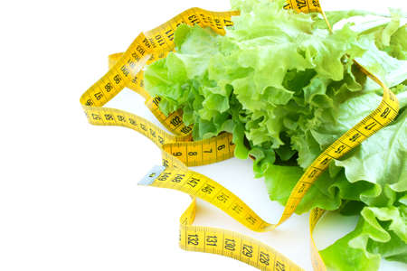 Green leaf lettuce and tape measure. The concept of losing weight. Salad leaves and tape measure isolated on white background.の写真素材