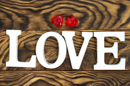 inscription love in wooden letters on a dark wooden background and two hearts. Preparing a card for Valentine's Day. Flat layout.の写真素材