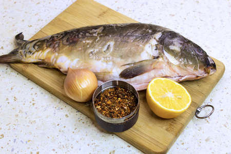 Carp. Preparing fish for baking. Carp with lemon and spices on onion rings. Cooking lunch, dinner. Top view.の写真素材