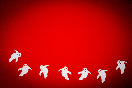 Halloween on a red background. Silhouettes of ghosts on red. Copy space. Greeting card mockup.