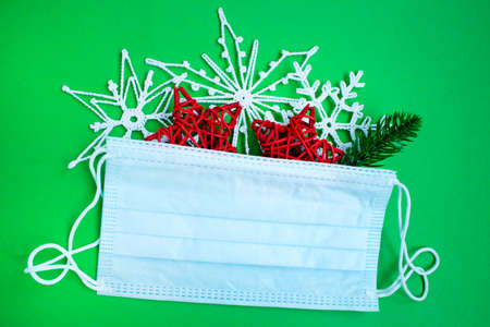 Winter holidays with coronavirus. Face mask and Christmas decorations. Concept for celebrating Christmas and New Year during a pandemic.の写真素材