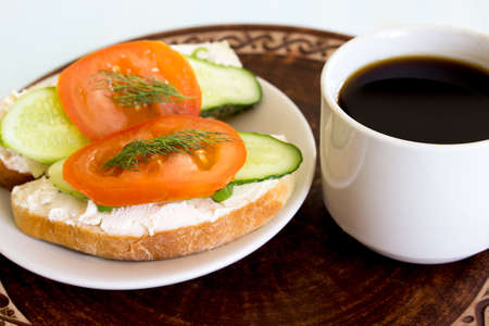 Cup of coffee and vegetable sandwiches. Cucumber, tomato and cream cheese on homemade bread. Traditional breakfast. Vegetarianism concept. Close-up.の写真素材