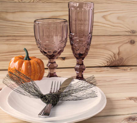 Traditional Halloween table setting in rustic style. Fork, knife, glasses and plates on a wooden background. Celebration concept. Close-up.の写真素材