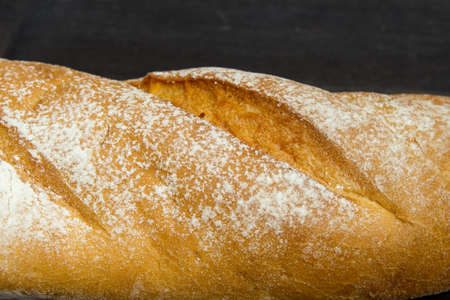 Baguette. Fresh golden baguette on an old wooden table. Close-up. French traditional bread on a dark background. Top view. Copy space.の写真素材