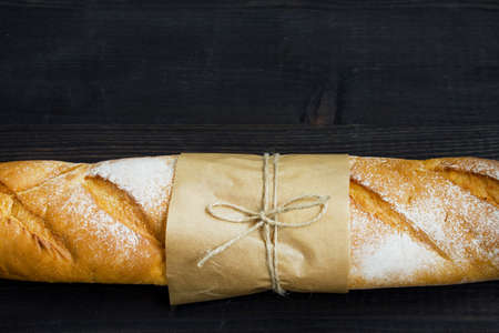 Baguette. Fresh golden baguette on an old wooden table. Close-up. French traditional bread on a dark background. Top view. Copy space.の写真素材