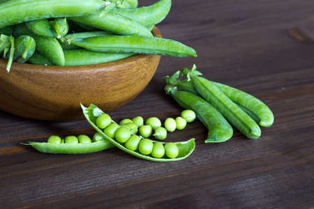 Pods of green peas in a wooden bowl. seasonal products. Products from local producers. Vegetarianism. copyspace. close-up. selective focus.の写真素材