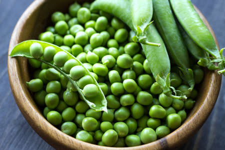 Green peas in a wooden bowl. seasonal products. Products from local producers. Vegetarianism. close-up. selective focus.の写真素材